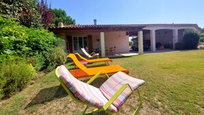 A patio with lounge chairs and a covered area with tables and chairs.