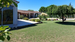 A house with a tiled roof, a covered patio, and a well-maintained lawn.