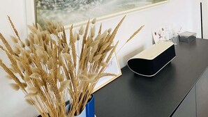 A modern room with a large abstract painting, a vase with dried plants, and a sleek black console table. - La Baïta spacious house 200m from the beach (Trégastel)