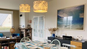 A dining area with a striped tablecloth, wooden chairs, and hanging pendant lights. - La Baïta spacious house 200m from the beach (Trégastel)