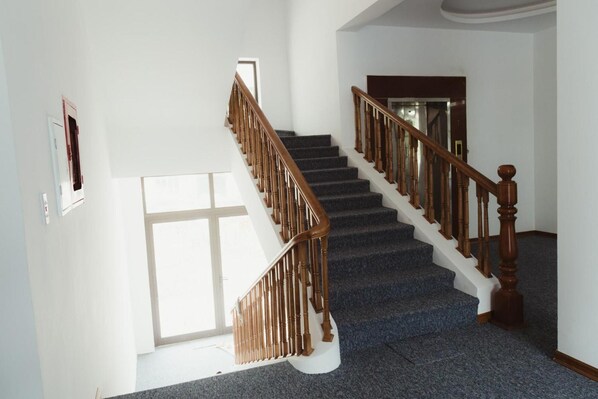 Una escalera con balaustres de madera y un rellano alfombrado.