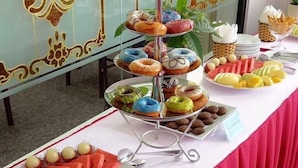 Ein Buffet mit verschiedenen Speisen, darunter Donuts, Früchte und Gebäck.