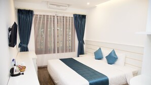 Ein Hotelzimmer mit Bett, Nachttisch, Wasserkocher, Korb und Fenster mit Vorhängen.