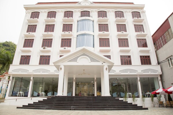 A multi-story building with a central entrance, large windows, and a staircase leading to the entrance. - Windsor Hotel Son La (To Hieu)