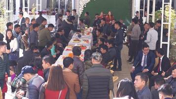 A crowded outdoor dining area with tables set for a meal, surrounded by a green wall and a sign reading "WIND&OR HOTEL".