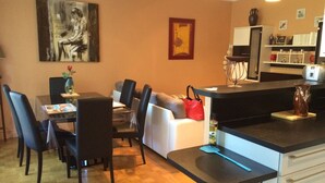Cozinha moderna com bancada preta, armários brancos e área de jantar com mesa e cadeiras.