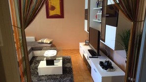 Uma sala de estar moderna com sofá, mesa de centro, televisão de tela plana e rack com controle remoto.