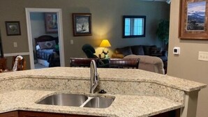 Una cocina con encimeras de granito, un lavamanos doble y armarios de madera.