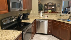 Cocina con encimeras de granito, electrodomésticos de acero inoxidable, gabinetes de madera y lavavajillas.