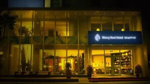 The exterior of the Merry Nest Hotel with a well-lit entrance and visible indoor seating area. - Merrynest Hotel (Guangzhou)