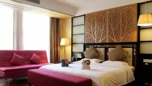 A hotel room with a bed, a red sofa, a small table, and a decorative wall panel. - Merrynest Hotel (Guangzhou)