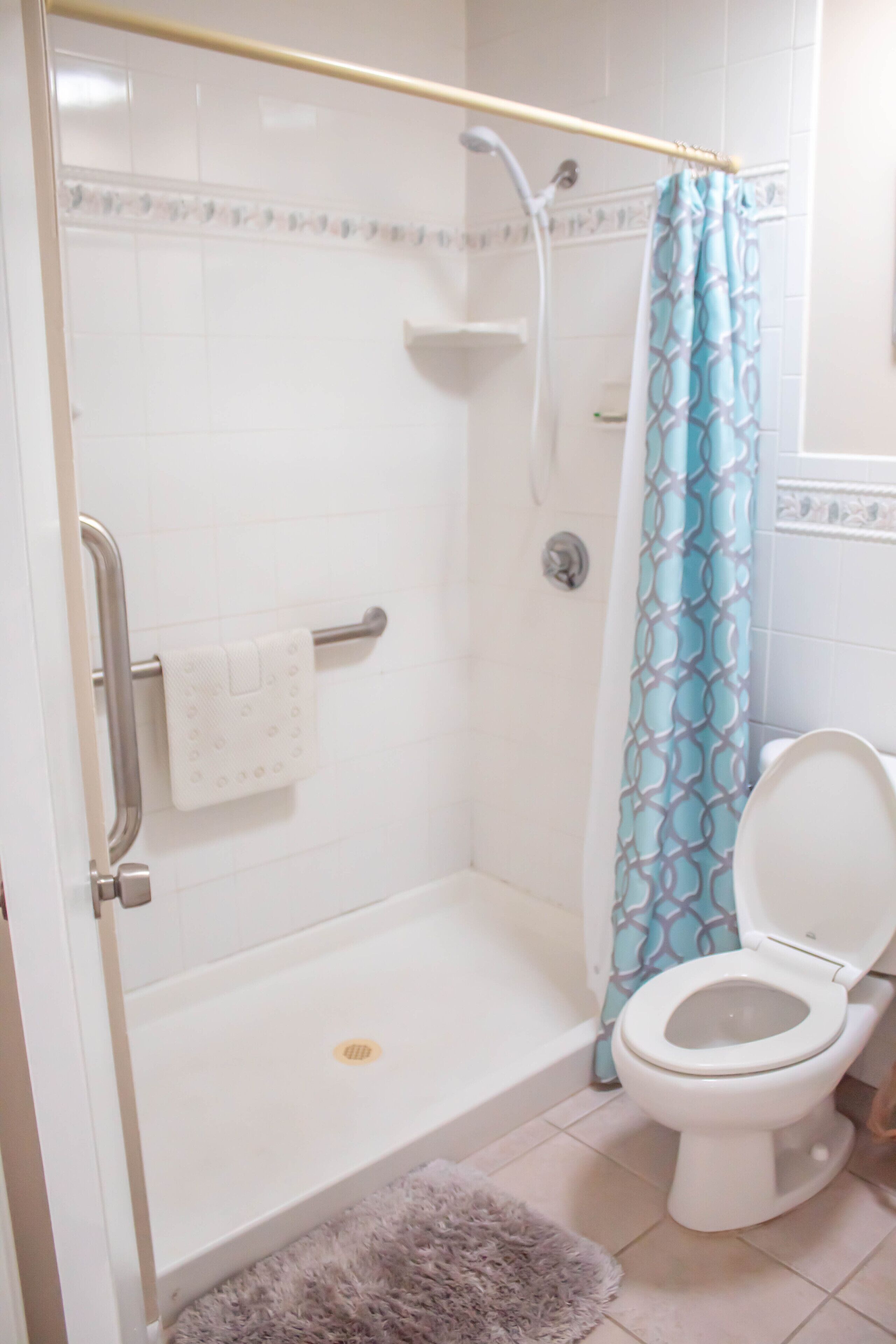 A bathroom with a shower, toilet, and a towel rack.