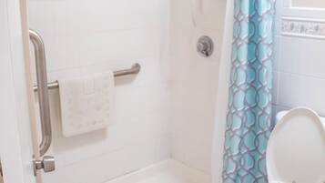 A bathroom with a shower, toilet, and a towel rack.