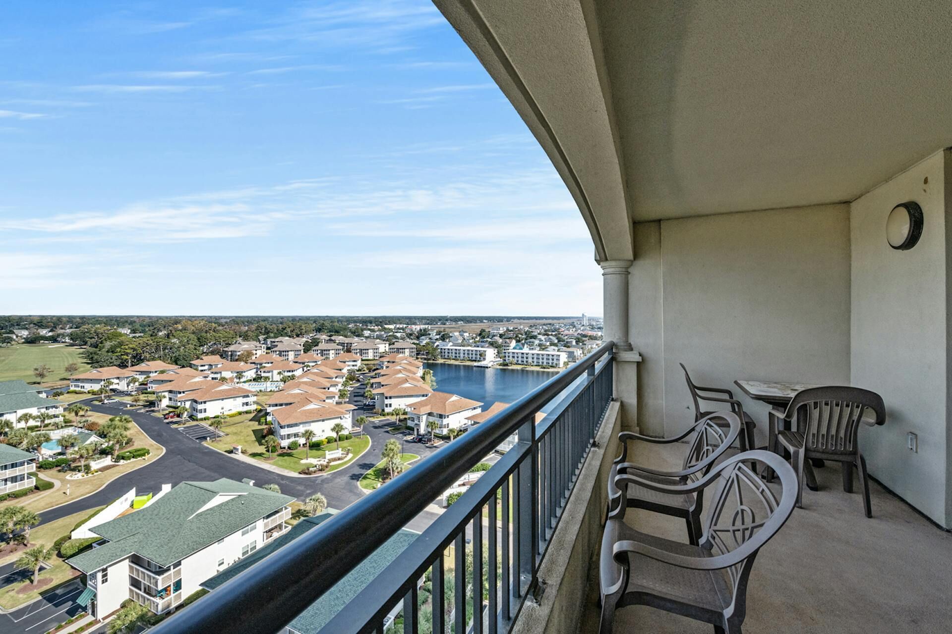 A balcony with a view of a residential area and a body of water.