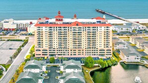 Un hôtel de grande hauteur doté de nombreux balcons, offrant une vue sur le front de mer et comprenant une jetée qui s’avance dans l’eau.