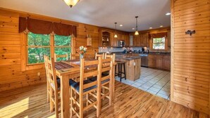 L’intérieur d’un chalet en bois comprend un coin repas, une cuisine et de grandes fenêtres.