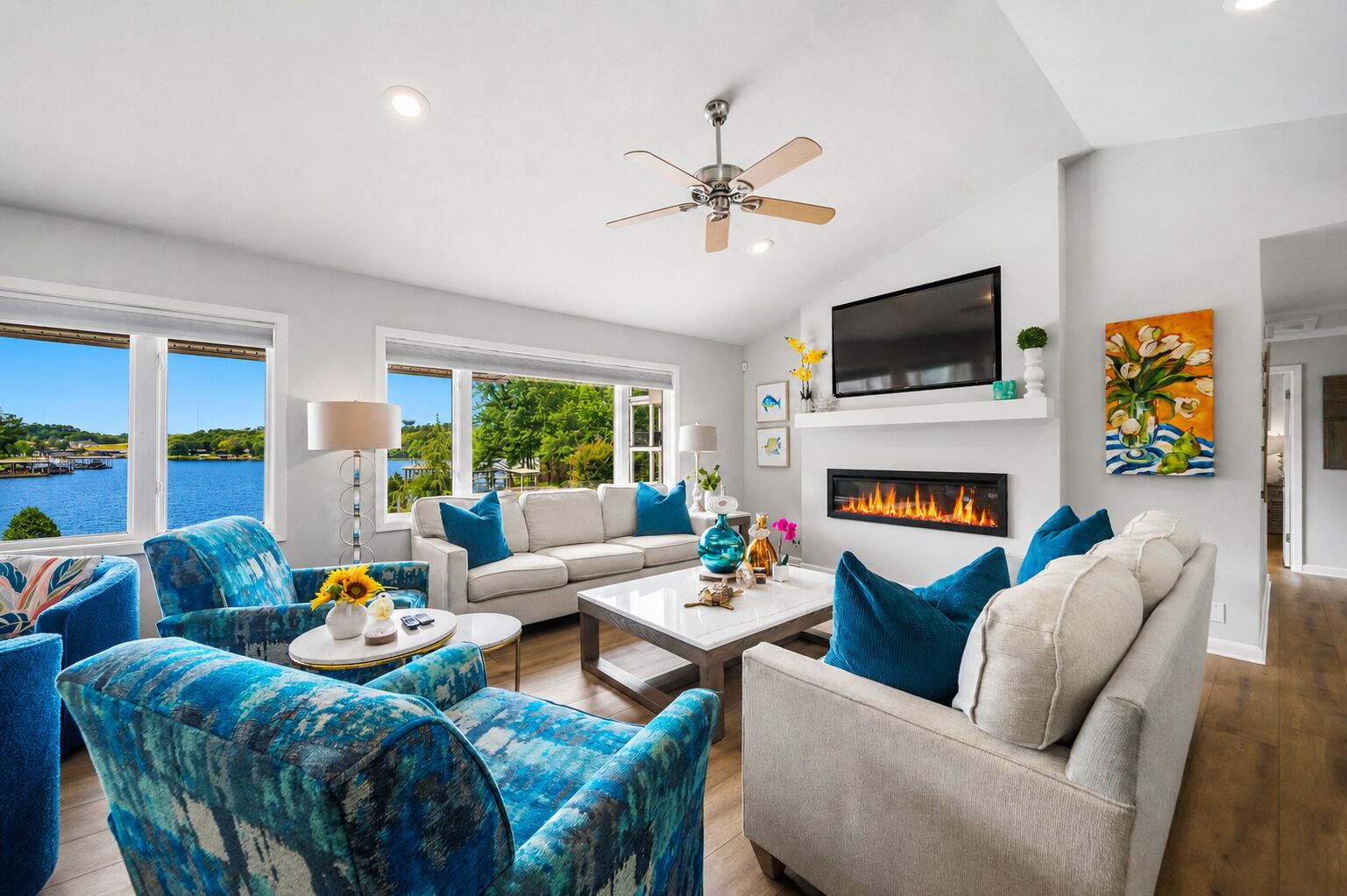 A modern living room with a fireplace, a ceiling fan, and a large TV.