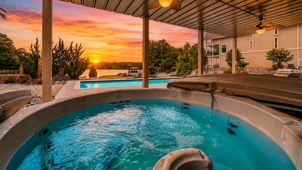 A hot tub under a covered area with a sunset view. - "Bayshore Breeze" - Lakefront 7BR, Private Pool, Hot Tub, Putting Green, Views (Hot Springs)