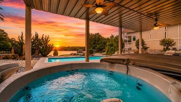 A hot tub under a covered area with a sunset view.