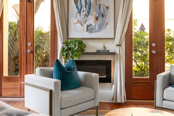 A modern living room with a fireplace, a sofa with teal cushions, and a large abstract painting above the fireplace.