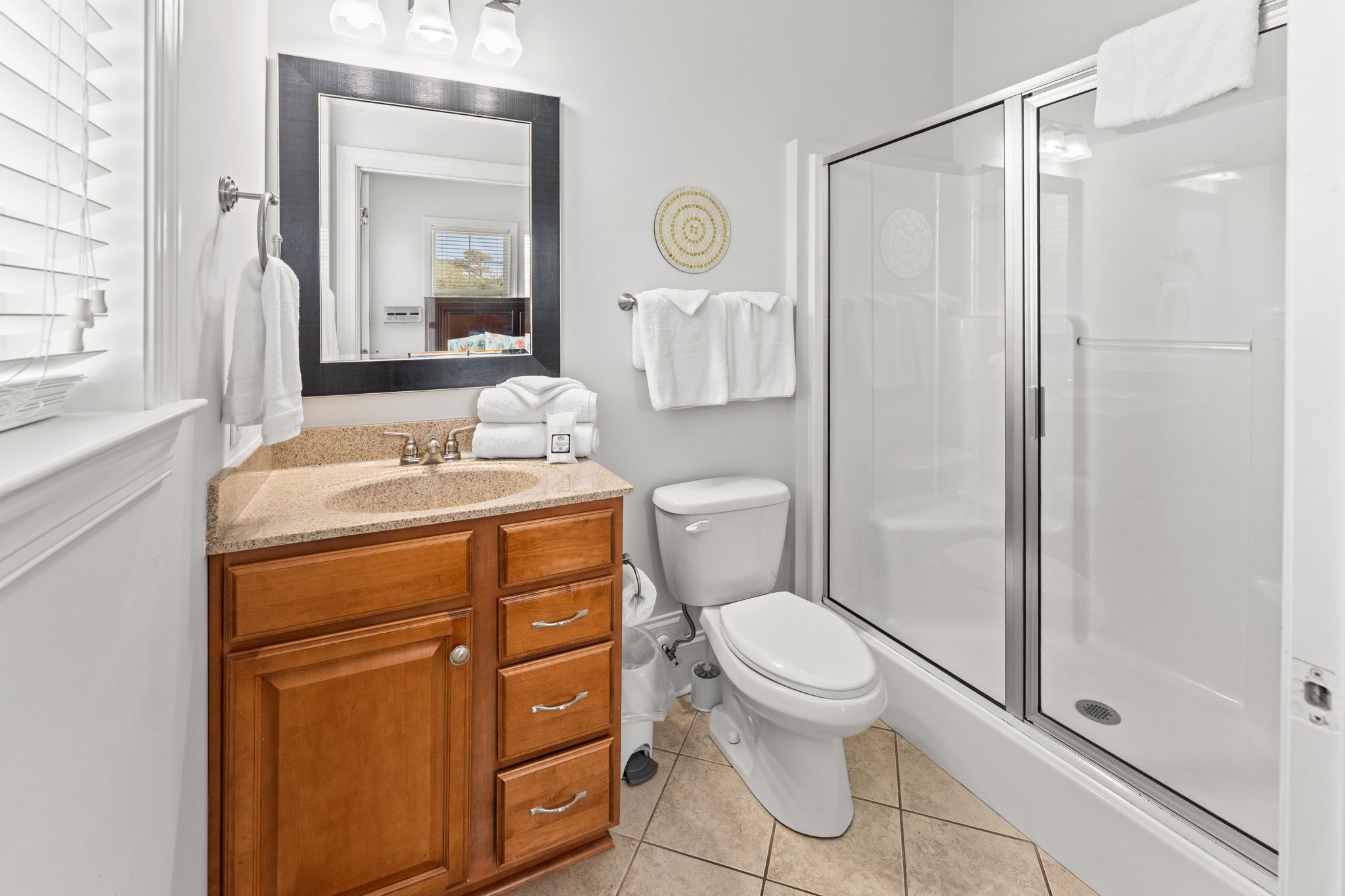 Une salle de bain avec un meuble-lavabo en bois, des toilettes, une douche en verre et un grand miroir.