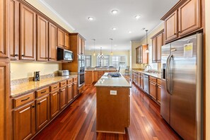 Una cocina amplia con armarios de madera, electrodomésticos de acero inoxidable y una isla central.