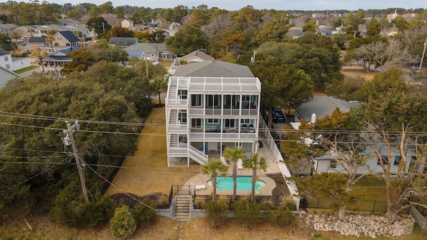 Une maison à plusieurs étages avec une piscine, entourée d’arbres et d’autres maisons.