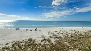 Una playa con cielo despejado, orilla arenosa y algunas personas.