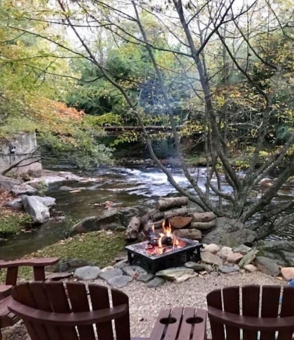 Un área de estar al aire libre junto al río, con un brasero y sillas.