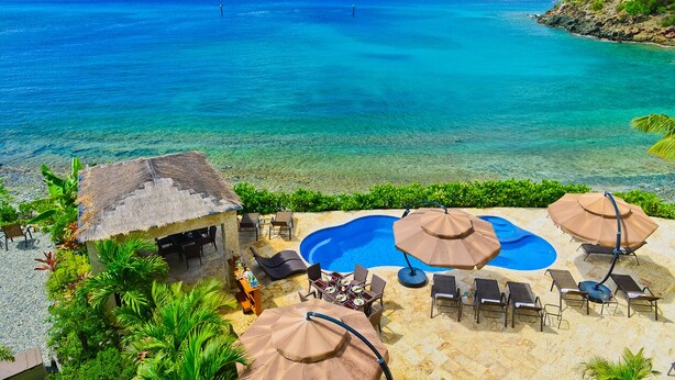 Un resort con piscina, sillones de descanso y vista al océano.