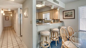 Una cocina moderna con una isla central, taburetes de bar y una mesa de comedor.