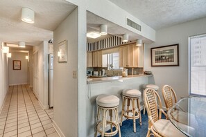 A modern kitchen with a central island, bar stools, and a dining table.