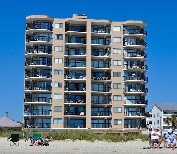 A multi-story hotel with balconies, each with outdoor seating.