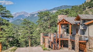 A mountain lodge with a stone facade, wooden balconies, and a staircase leading to the entrance. - Stunning Home!  Rare Views & Ultimate Privacy – Perfect Location Bordering RMNP! (Estes Park)