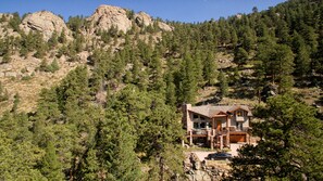 A mountain cabin with a stone exterior, large windows, and a car parked in front. - Stunning Home!  Rare Views & Ultimate Privacy – Perfect Location Bordering RMNP! (Estes Park)