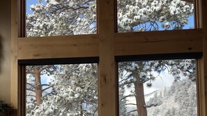 A room with large windows offering a view of snow-covered trees and a balcony. - Stunning Home!  Rare Views & Ultimate Privacy – Perfect Location Bordering RMNP! (Estes Park)