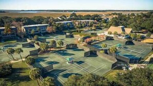 Vista aérea de una zona residencial con varias canchas de tenis, casas y zonas verdes.
