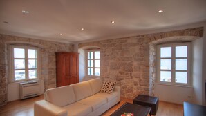 Un salon avec un mur en pierre, un canapé blanc, un meuble en bois et une table basse.