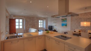 Une cuisine moderne avec un mur en pierre, une cuisinière encastrée et un coin repas comprenant une table et des chaises.