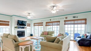A spacious living room with a fireplace, multiple seating areas, and large windows with blinds. - 3-Story Oceanfront • Breathtaking Views • Dogs OK (Norfolk)