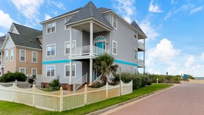 A two-story house with a balcony, a porch, and a small garden. - 3-Story Oceanfront • Breathtaking Views • Dogs OK (Norfolk)