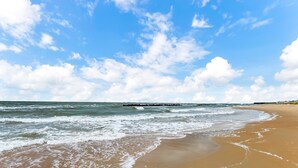 A beach with waves, a clear sky, and a distant pier. - 3-Story Oceanfront • Breathtaking Views • Dogs OK (Norfolk)