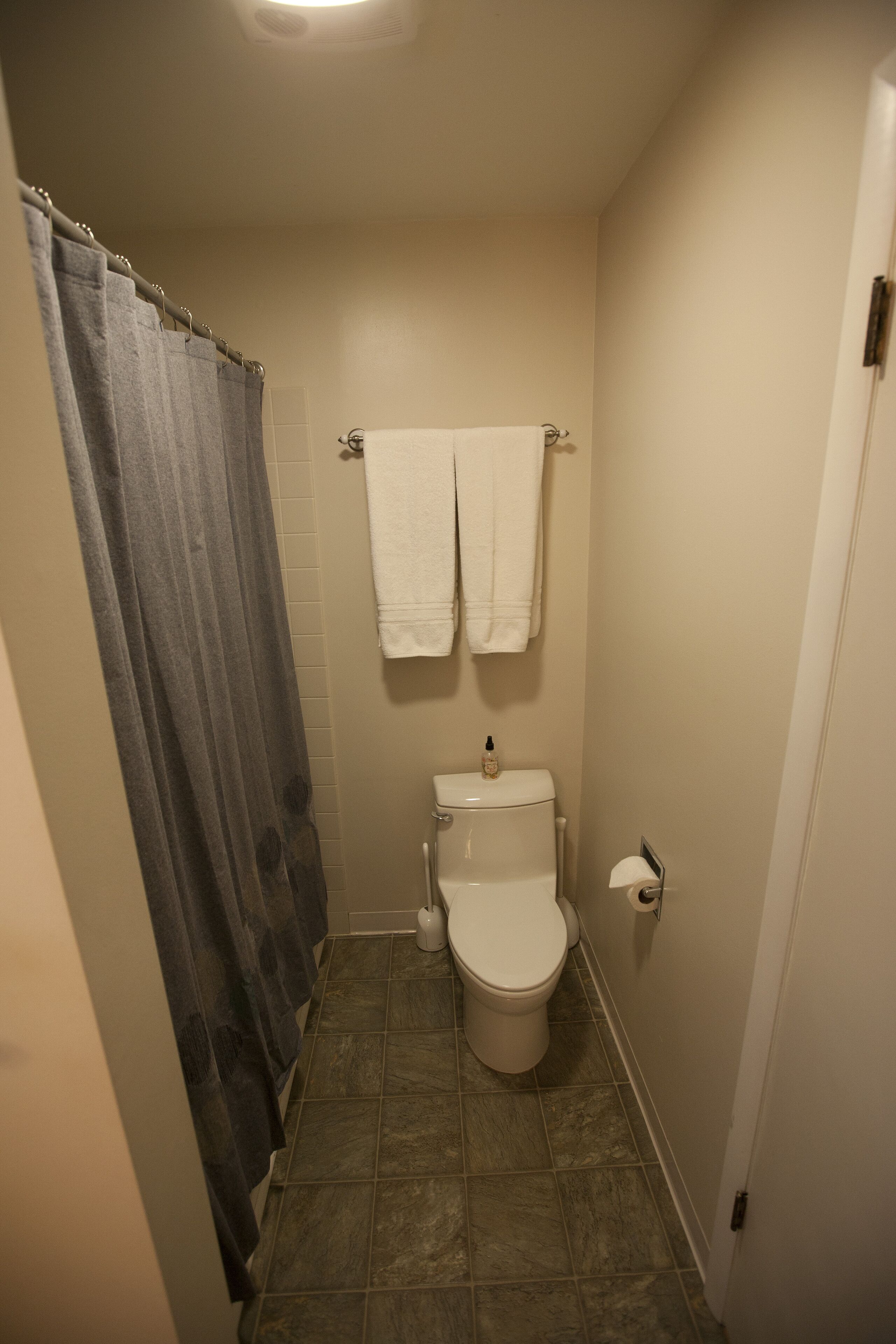 Un baño pequeño con inodoro, cortina de ducha y dos toallas colgadas en la pared.
