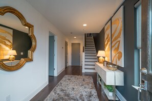 Experience a blend of classic and contemporary design in this inviting space, featuring a grand mirror, console table, and staircase.