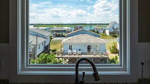 A window with a view of a residential area, including houses and a body of water. - Next to Sea Gallery | Group Favorite! Ocean Front + Original Artwork (Topsail Beach)