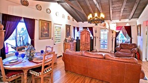 Ein gemütliches Wohnzimmer mit Holzbalkendecke, eine Essecke mit Tisch für zwei Personen und ein bequemes Sofa.