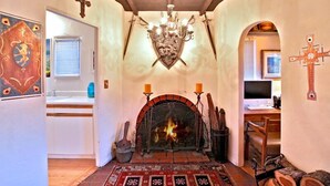 Ein gemütliches Interieur mit Kamin, einer Kristallleuchtre und einer rustikalen Holzbalkendecke.