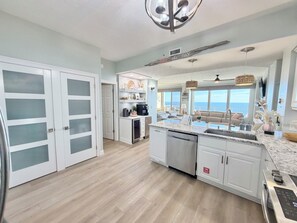 A modern kitchen with a large island, white cabinetry, and a view of the ocean. - Gulf Front with 40' Balcony waiting on you! (Panama City Beach)