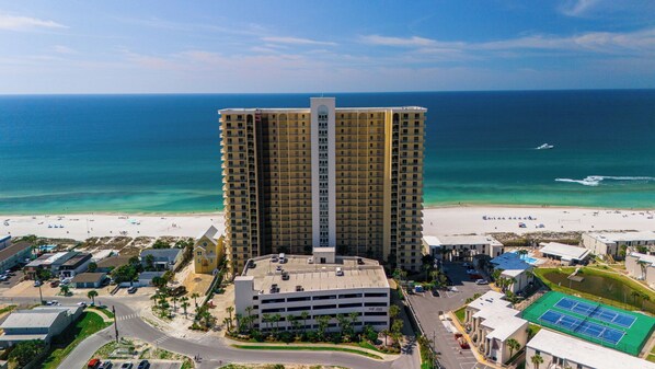 A high-rise hotel with a central atrium, a parking garage, and a beach view.