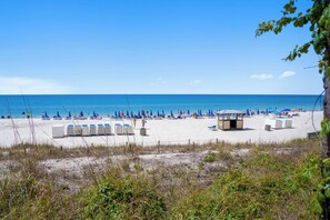 Une plage de sable blanc, avec des parasols bleus et des chaises longues.